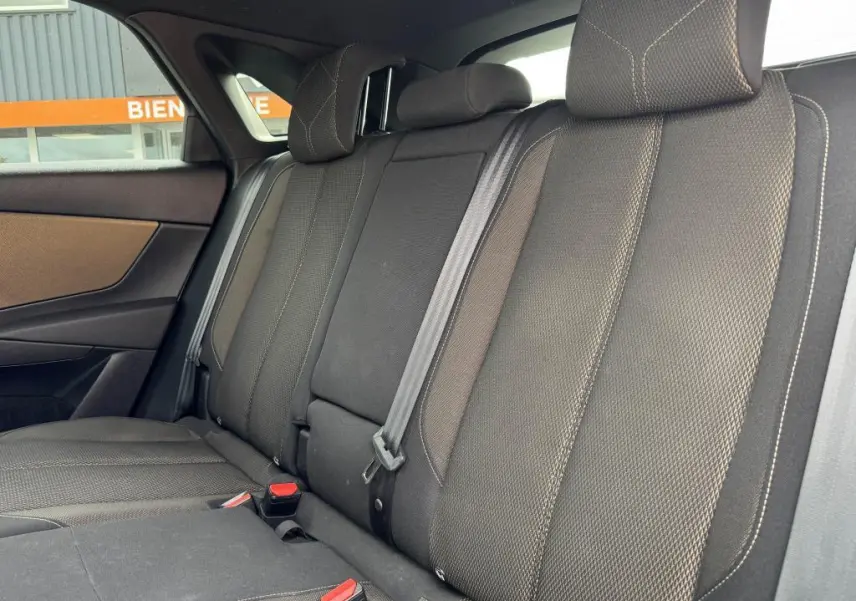 Vue latérale droite de la banquette arrière en tissu bronze du DS7 Crossback gris, avec appuie-têtes et ceintures visibles.