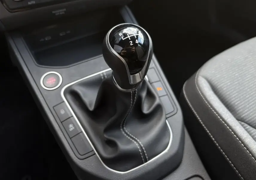 Le levier de vitesses manuel noir de la SEAT IBIZA TSI 115 Xcellence 2025, entouré de commandes et siège tissu gris.