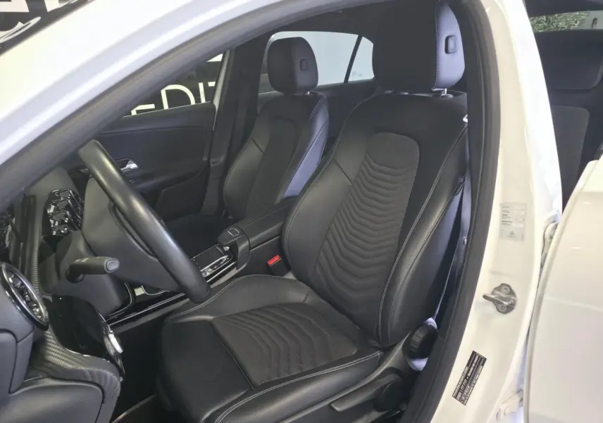 Vue intérieure côté conducteur d'une Mercedes Classe A 160 Style Line blanche avec sièges noirs en tissu et similicuir.