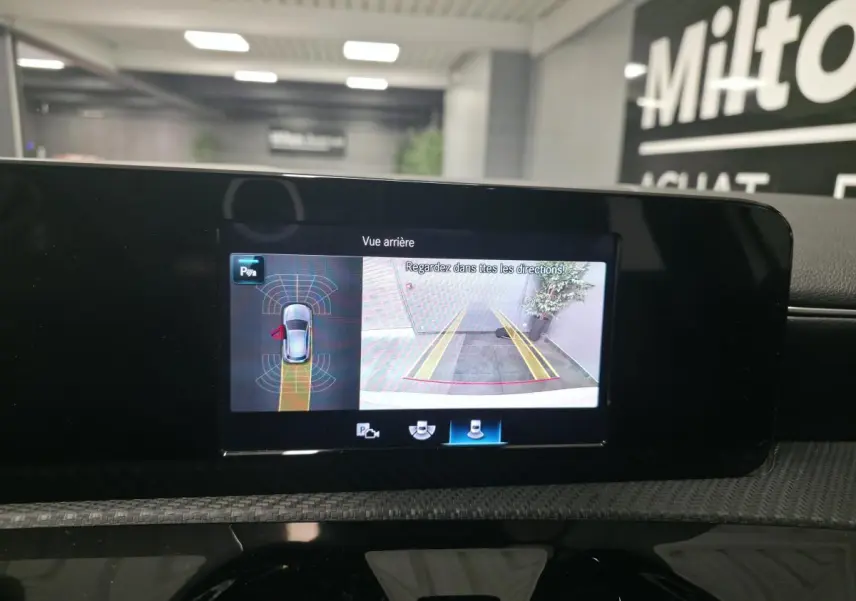 Écran multimédia affichant la caméra de recul et l’aide au stationnement du Mercedes Classe A blanc, vue intérieure centrale.