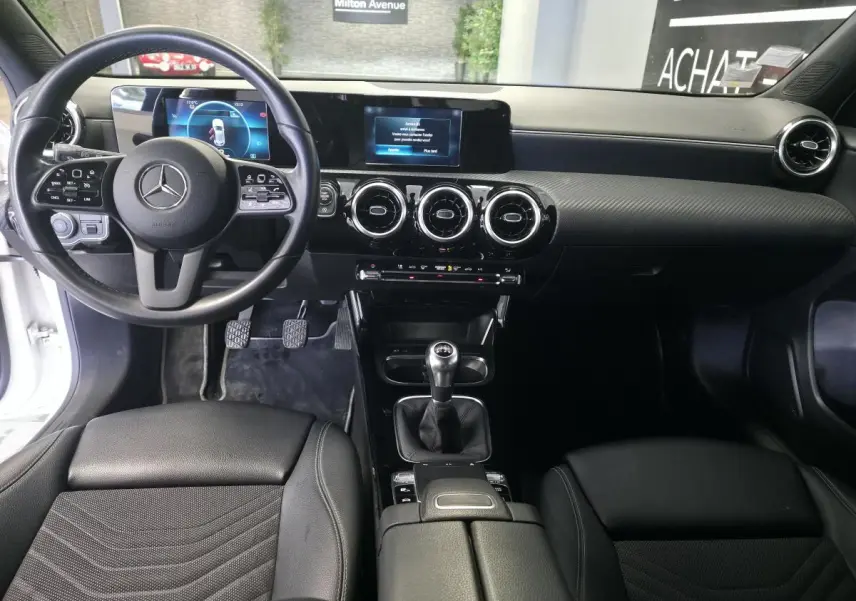 Intérieur noir de la Mercedes Classe A 160 Style Line 2019, vue avant centrée sur le tableau de bord et la boîte manuelle.