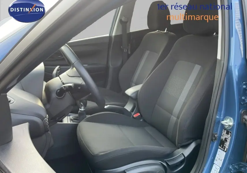 Vue intérieure côté conducteur de la Hyundai i20 2025 bleu vibrant metal, montrant les sièges noirs et le volant.