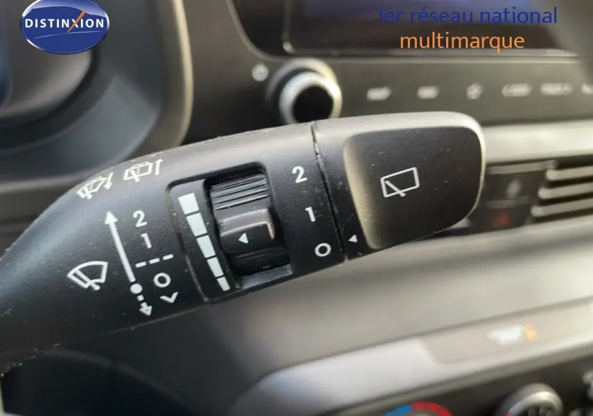 Gros plan sur la commande des essuie-glaces du Hyundai i20 2025 en Bleu Vibrant Metal, intérieur tableau de bord flou.