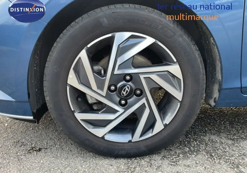 Gros plan sur la roue avant gauche d'une Hyundai i20 Bleu Vibrant Metal, mettant en valeur la jante au design géométrique.