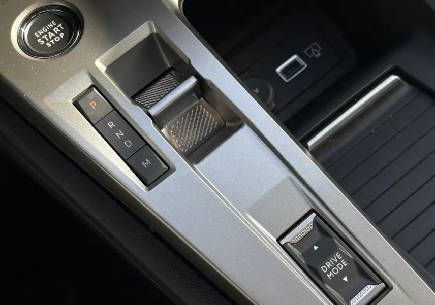 Vue rapprochée de la console centrale argentée de la Peugeot 308 Hybrid avec sélecteur de boîte auto et bouton Drive Mode.
