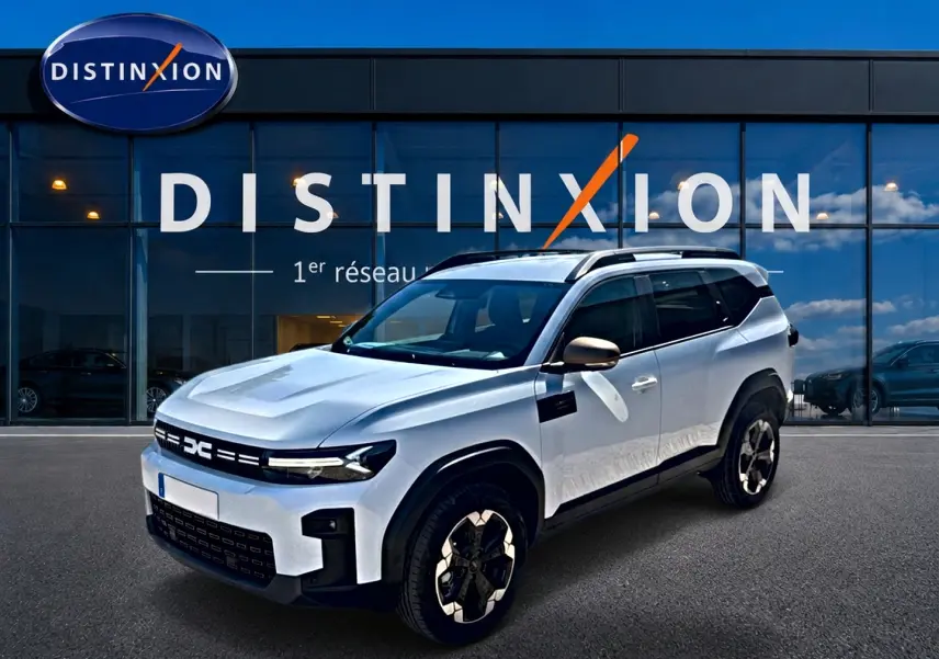 SUV Dacia Bigster blanc en 3/4 avant droit, avec jantes alu et barres de toit noires visibles.