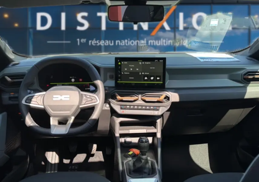 Intérieur avant du Dacia Bigster blanc 2026, vue du poste de conduite avec volant multifonction et écran tactile central.