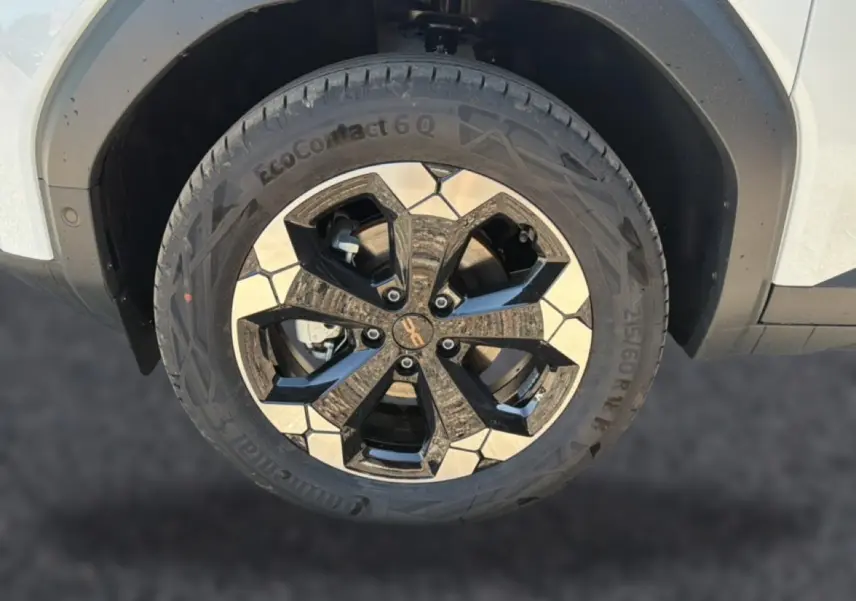Gros plan sur la roue avant droite blanche du Dacia Bigster avec jante alu bicolore noire et argentée.