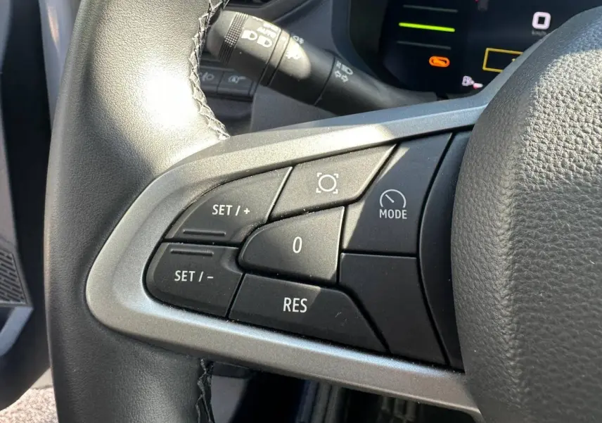 Gros plan sur les commandes noires du volant multifonction côté gauche du Dacia Duster 2025 couleur Sandstone.
