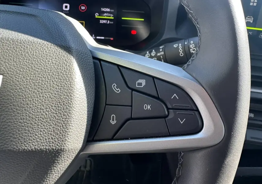 Gros plan sur les commandes multifonctions à droite du volant du Dacia Duster 2025, intérieur noir et gris.