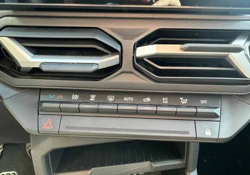 Vue rapprochée de la console centrale du Dacia Duster 2025, boutons de climatisation et sorties d’air noires.