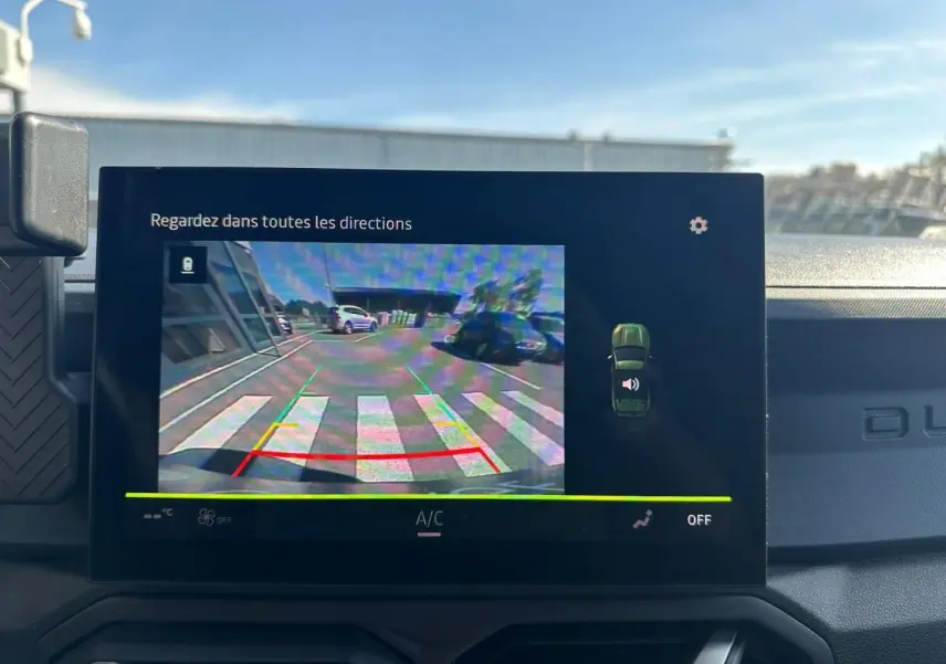 Écran tactile intérieur du Dacia Duster 2025 affichant la caméra de recul avec vue arrière en extérieur.