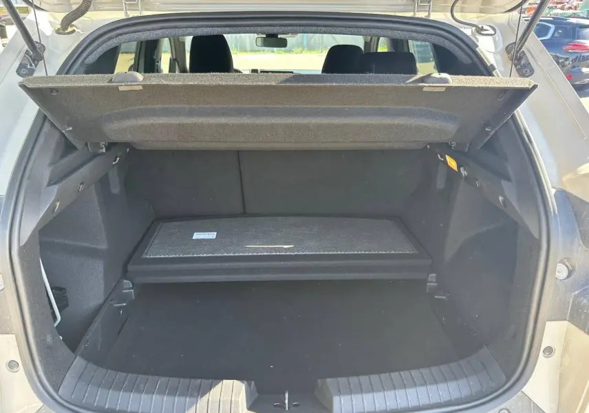Coffre ouvert du Dacia Duster 2025 couleur Sandstone, montrant le plancher de coffre mobile et la tablette cache-bagages.