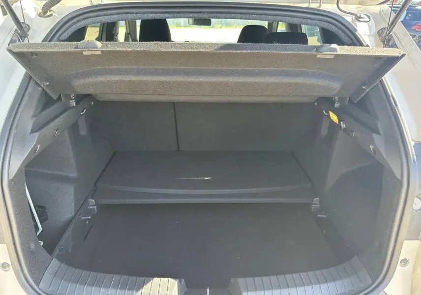 Coffre ouvert du Dacia Duster 2025 couleur Sandstone, montrant la tablette cache-bagages et l’espace de rangement.