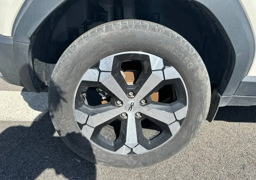 Gros plan sur la roue avant droite du Dacia Duster 2025 couleur Sandstone avec jante alu au design hexagonal.