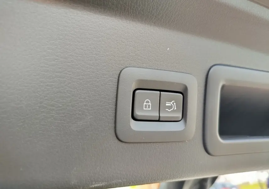 Gros plan sur les boutons de verrouillage et ouverture du coffre dans le coffre d'un Mazda CX-30 noir 2020.