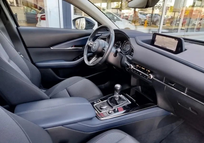 Intérieur noir de la Mazda CX-30 2020, vue côté conducteur, volant multifonction et écran GPS central visible.
