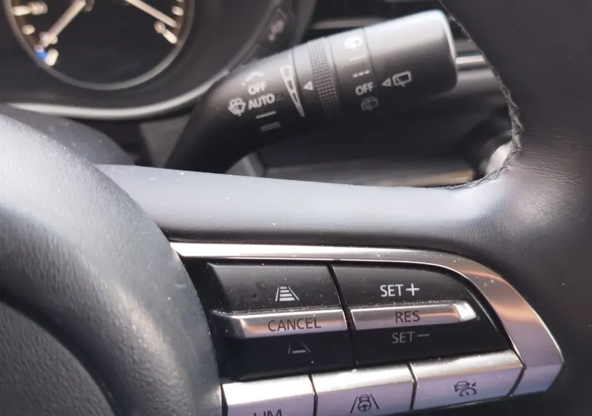 Gros plan sur les commandes au volant du Mazda CX-30 2020, mettant en valeur les boutons de régulateur de vitesse.