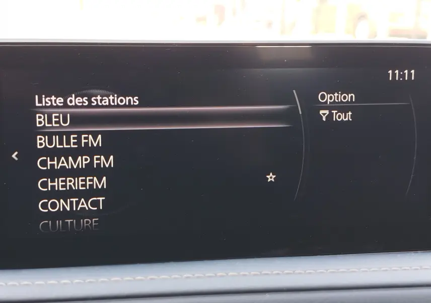 Écran multimédia intérieur du Mazda CX-30 affichant la liste des stations radio avec interface noire et texte blanc.
