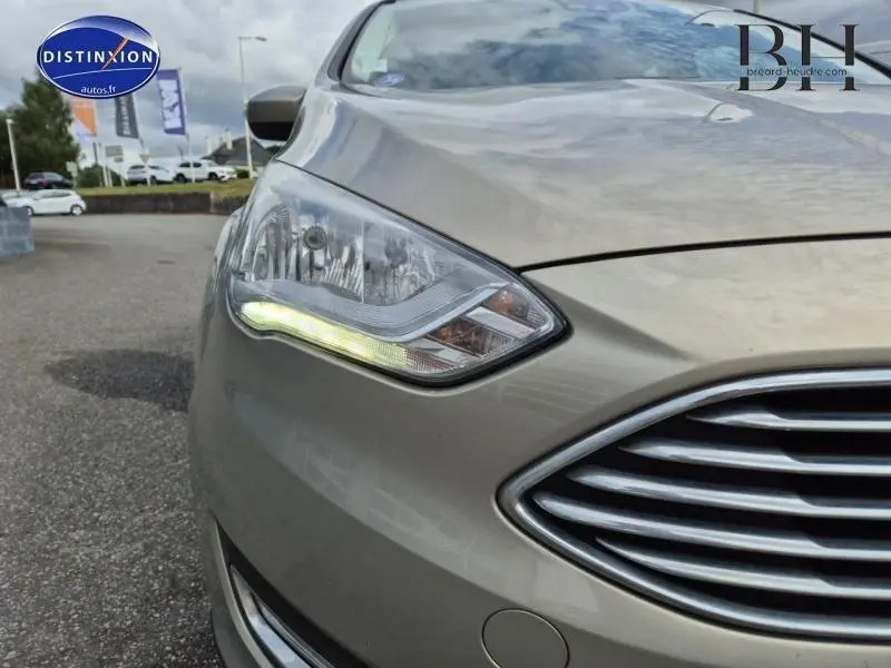 Gros plan sur le phare avant gauche d'une Ford C-MAX 2018 couleur Fashion Brun Caribou avec calandre chromée.