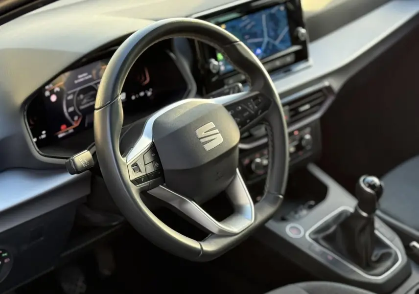 Vue rapprochée de l'intérieur de la SEAT Ibiza 2025, volant cuir multifonction et levier de vitesses manuelle visibles.