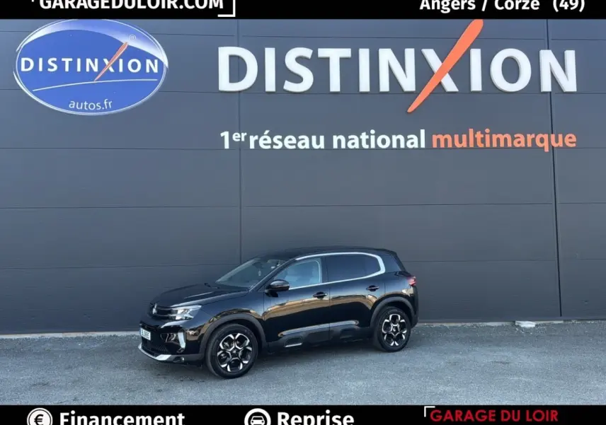 Vue de profil côté gauche d'un Citroën C5 Aircross noir 2025 stationné devant un mur gris avec logo Distinxion.