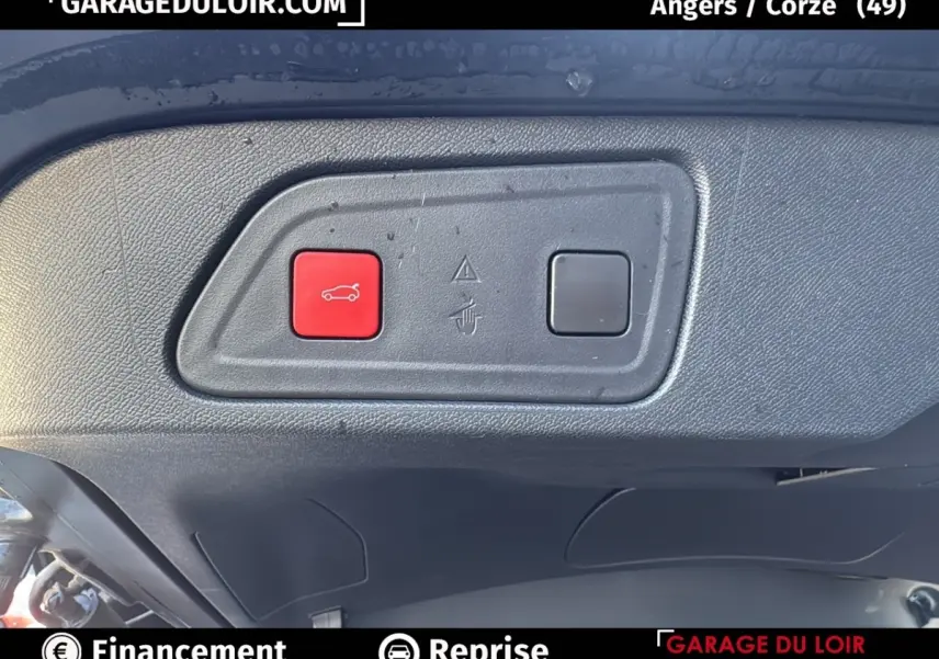 Gros plan sur le bouton rouge d'ouverture du coffre dans le coffre d'un Citroën C5 Aircross noir 2025.