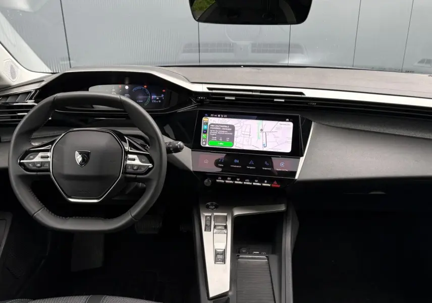 Vue intérieure avant du Peugeot 308 SW Hybrid 145 gris Artense, avec tableau de bord numérique et écran tactile central.