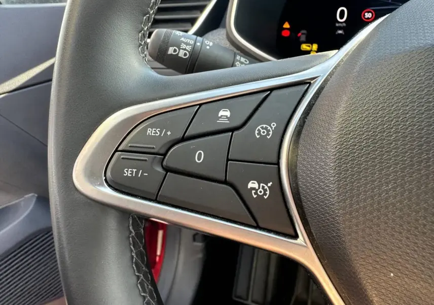Gros plan sur les commandes multifonctions du volant côté gauche de la Renault Clio Rouge Flamme 2025.