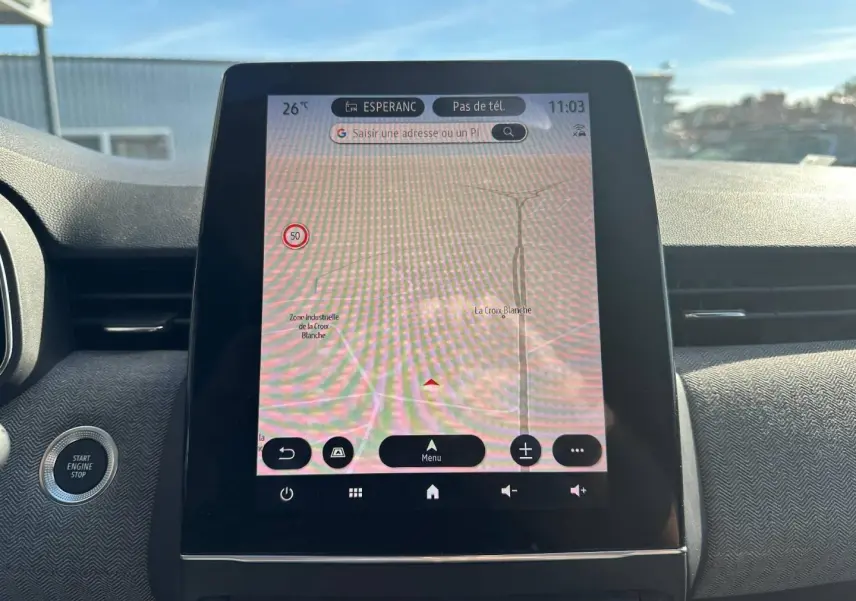 Vue intérieure centrée sur l’écran tactile GPS de la Renault Clio rouge flamme, avec bouton démarrage à gauche visible.
