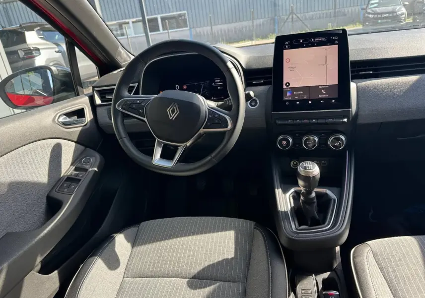 Vue intérieure côté conducteur de la Renault Clio 2025, volant multifonction et écran tactile central visibles.