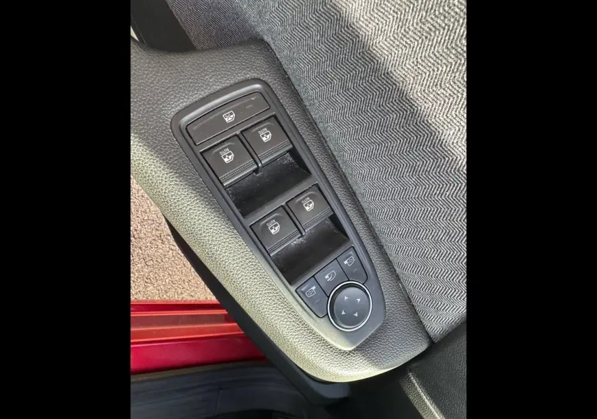 Détail des commandes des vitres électriques sur la porte avant gauche d'une Renault Clio Rouge Flamme 2025.
