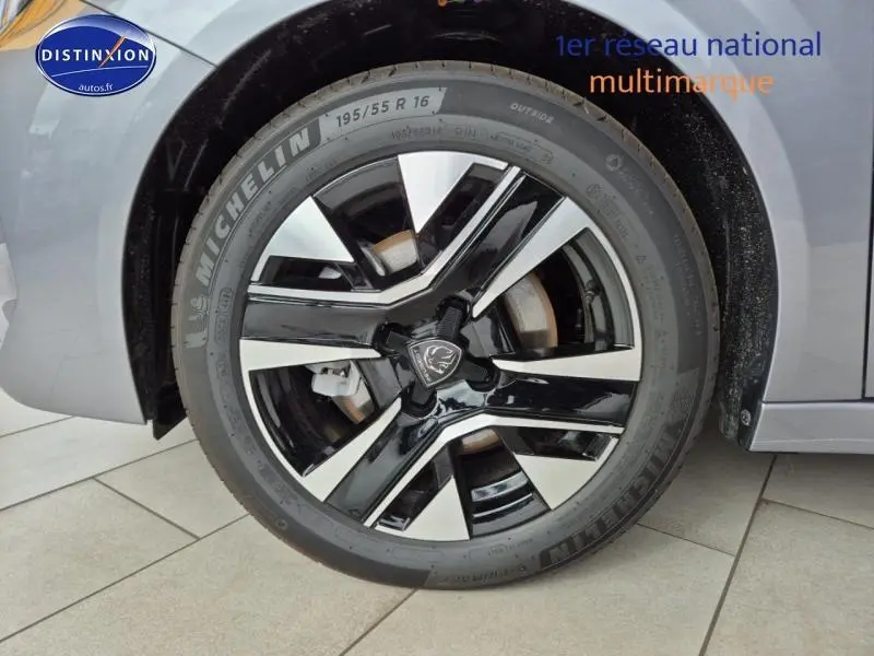 Gros plan sur la jante alu noire et argentée de la Peugeot 208 gris Artense, avec pneu Michelin visible au côté avant gauche.