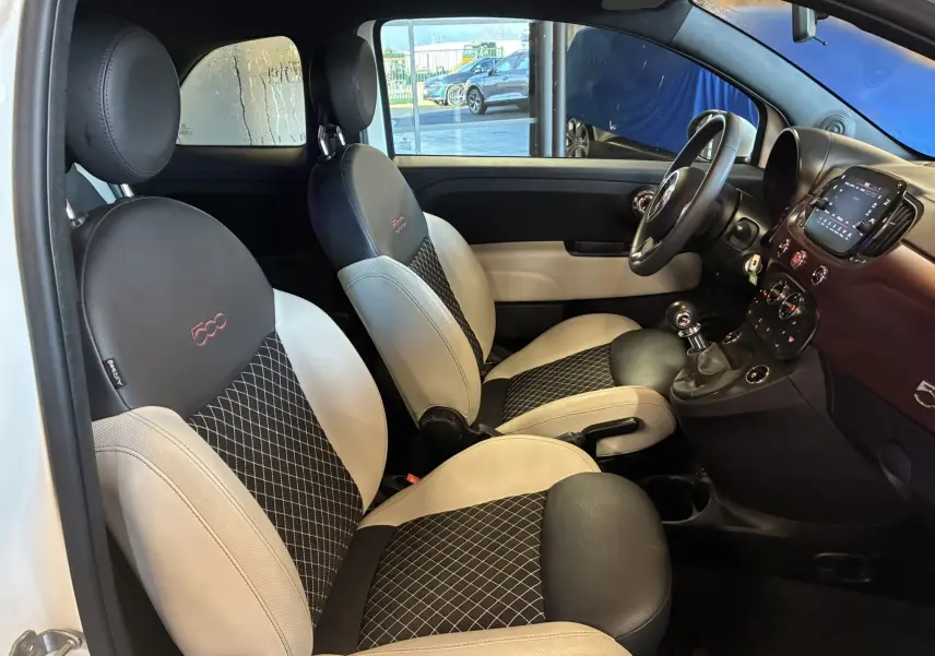 Vue intérieure côté gauche de la Fiat 500 blanche, mettant en valeur les sièges bicolores noirs et beige avec logo 500 brodé.