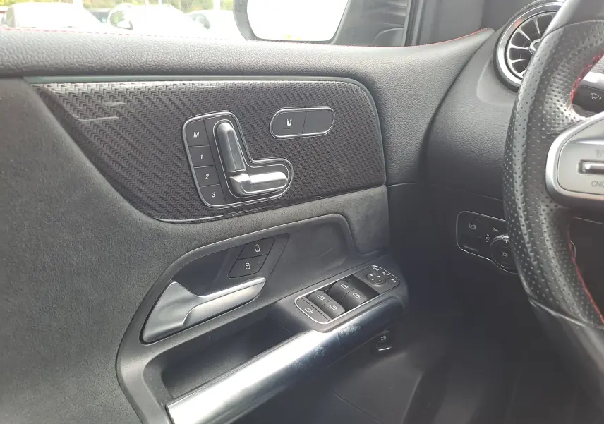 Détail de la porte côté gauche d'une Mercedes Classe B 2019 AMG Line, avec commandes de siège et finition carbone noire.