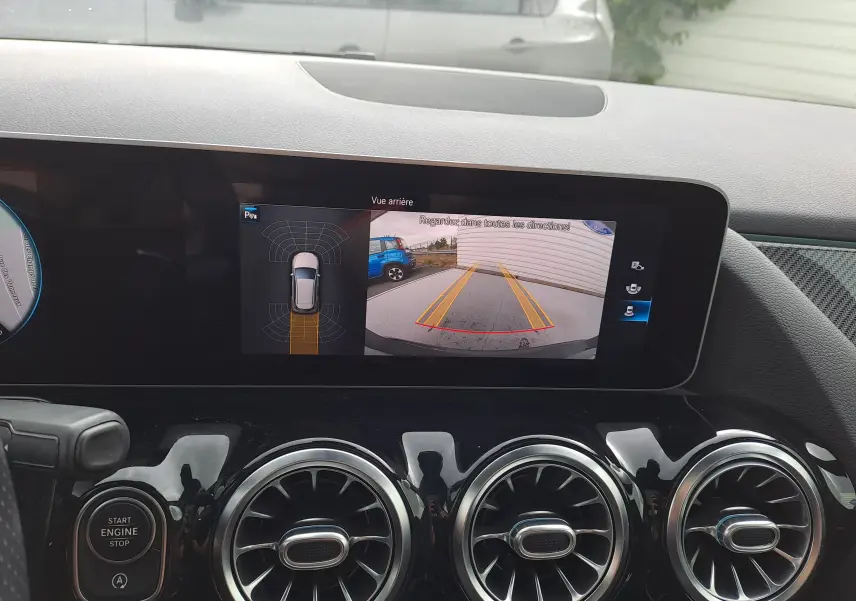 Tableau de bord de Mercedes Classe B 2019 avec écran affichant la caméra de recul et les aérateurs ronds chromés.