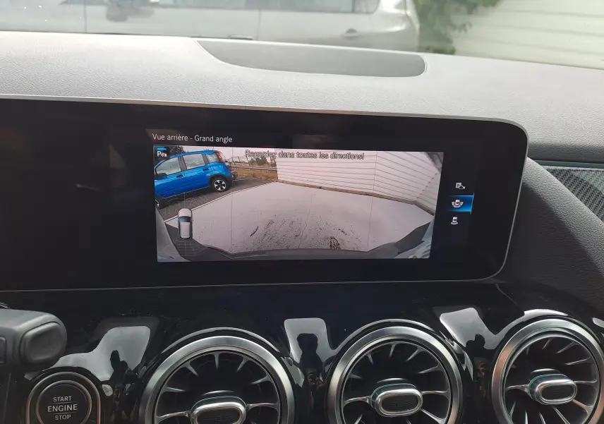 Écran intérieur de la Mercedes Classe B 2019 montrant la caméra de recul grand angle avec vue arrière et tableau de bord noir brillant.