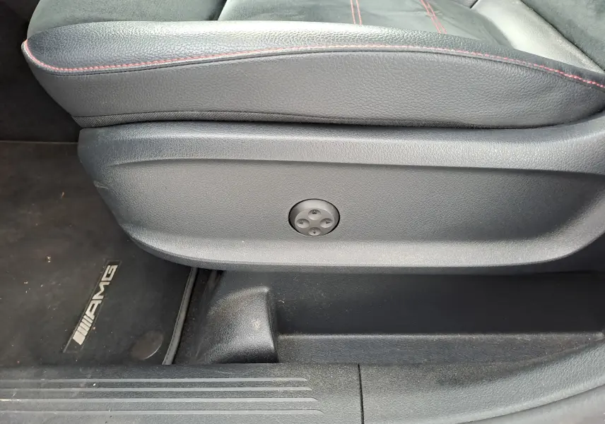 Gros plan sur la commande de réglage électrique du siège conducteur en cuir noir avec surpiqûres rouges dans une Mercedes Classe B AMG Line 2019.