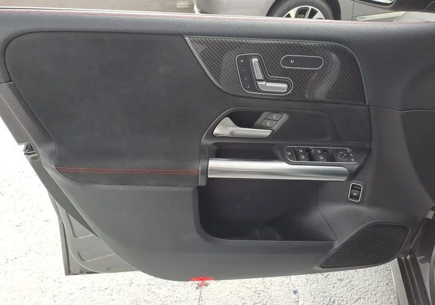 Gros plan sur la portière côté gauche de la Mercedes Classe B AMG Line 2019, revêtement noir avec surpiqûres rouges et commandes intégrées.