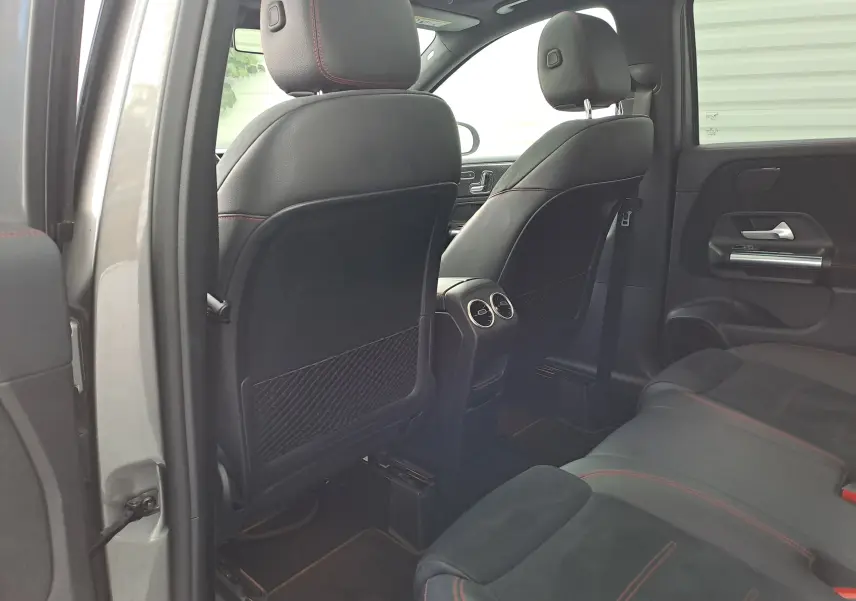 Vue intérieure arrière de la Mercedes Classe B AMG Line 2019, sièges noirs avec surpiqûres rouges et aérateurs centraux.
