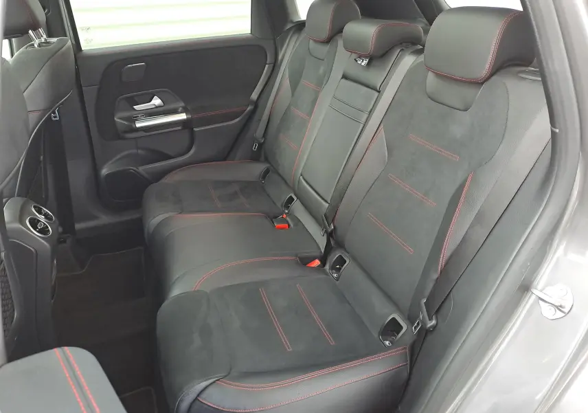 Vue intérieure arrière droite des sièges noirs en cuir et alcantara avec surpiqûres rouges d'une Mercedes Classe B AMG Line 2019 gris foncé métallisé.