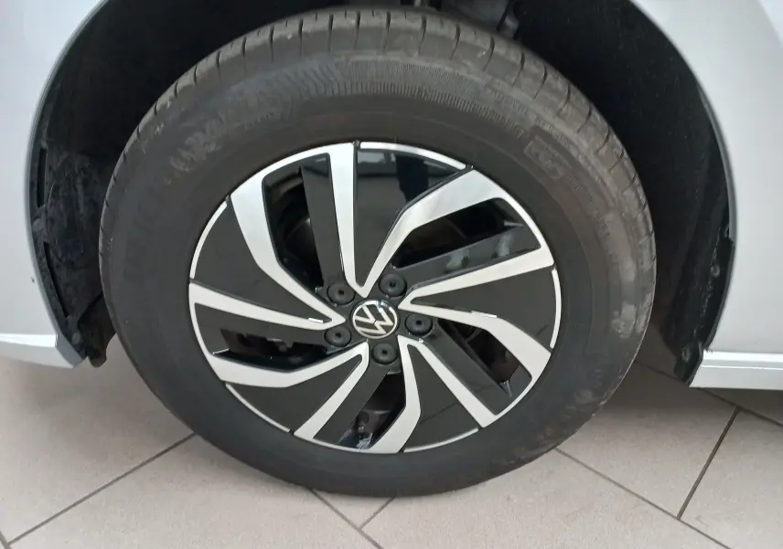 Gros plan sur la roue avant gauche d'une Volkswagen Polo 2024 couleur reflet d'argent avec jante alliage noire et argentée.