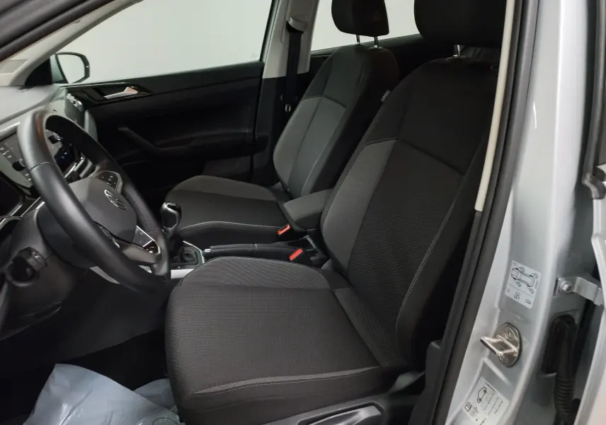 Intérieur avant droit d'une Volkswagen Polo 2024 reflet d'argent, sièges noirs et volant avec boîte manuelle visible.