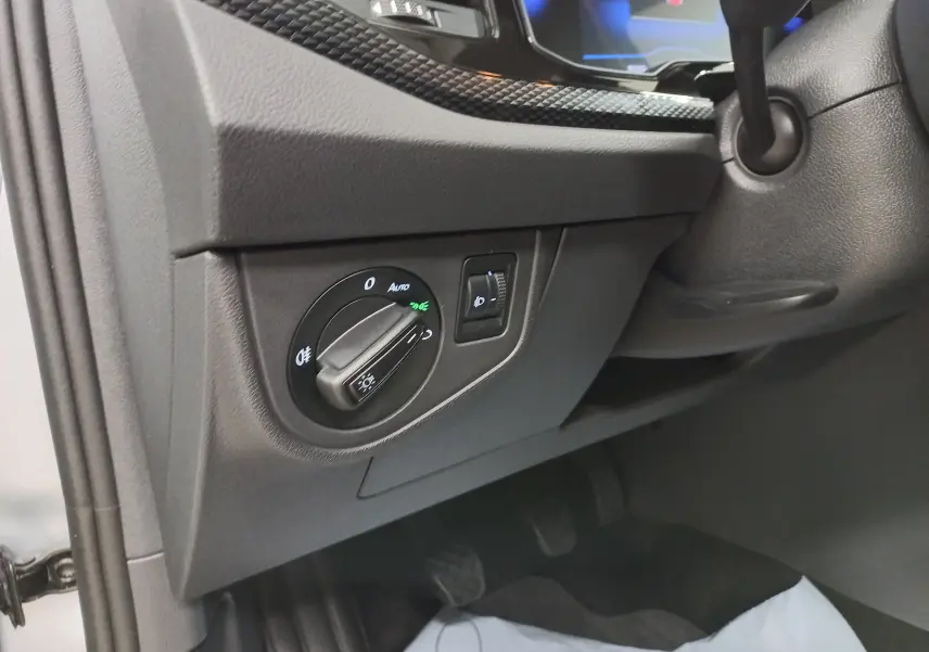Gros plan sur le tableau de bord côté gauche de la Volkswagen Polo 2024 en reflet d'argent, avec commande des phares et réglage d'intensité lumineuse.