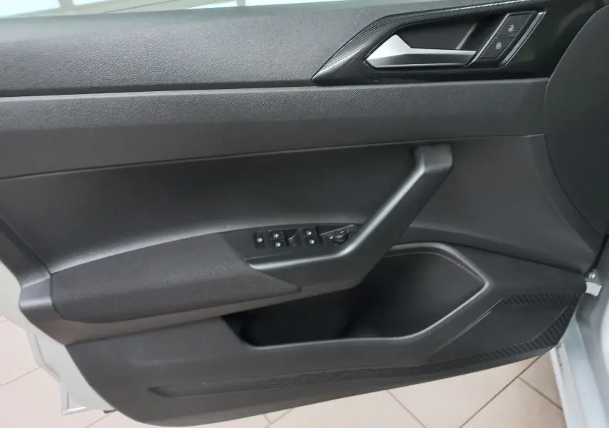 Intérieur de la porte côté conducteur d'une Volkswagen Polo 2024 reflet d'argent, avec commandes électriques et poignée noire.
