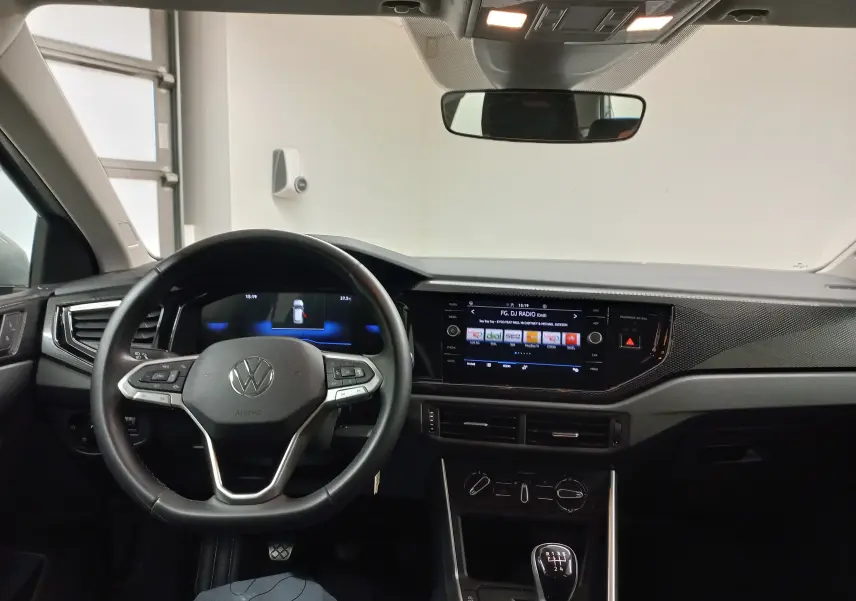 Vue intérieure frontale du tableau de bord et volant noir de la Volkswagen Polo 2024 avec écran tactile et boîte manuelle.