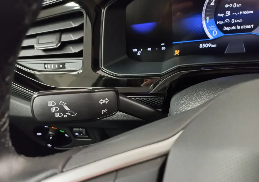 Gros plan sur le commodo gauche et le tableau de bord numérique d'une Volkswagen Polo 2024 couleur reflet d'argent.