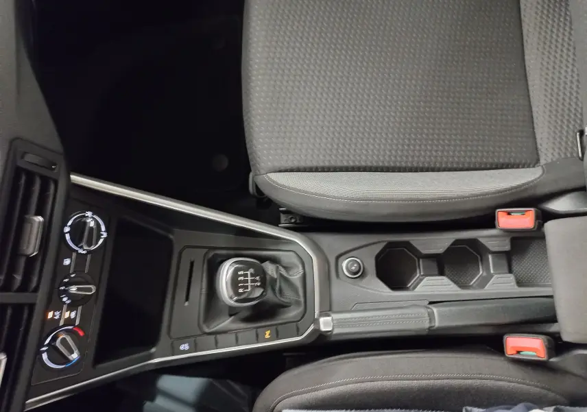 Vue plongeante sur la console centrale de la Volkswagen Polo 2024 avec levier de vitesse manuel et sièges gris foncé.