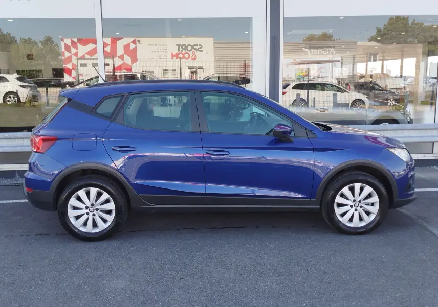 Vue latérale droite d'une SEAT Arona bleu électrique de 2019 avec jantes alliage et détails noirs sur les bas de caisse.