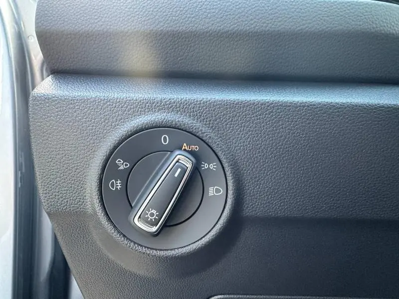 Gros plan sur la commande des phares noire avec réglage automatique dans l'habitacle du Volkswagen T-Roc 2025.